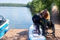 Sports instructor helping man with disability getting on paddle board