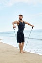 Sports. Man Doing Expander Exercises Outdoor On Beach. Body Workout