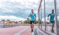 Sports man runs in jump workout, glass windows in background, runner in sportswear, a summer afternoon training in city