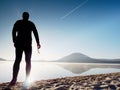 A sports man staying at the gorgeous sunset beach with glasses in hand and enjoying sunset Royalty Free Stock Photo