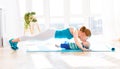 Sports mother is engaged in fitness and yoga with baby at home