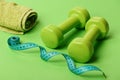 Sports regime symbols. Dumbbells in green color, twisted measure tape Royalty Free Stock Photo