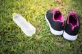 Sports shoes and bottle of water on grass background. Sports accessories.