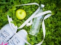 Sports Shoes Sneakers, Bottle Of Water And Apple On Fresh Green Grass