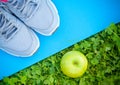 Sports Shoes Sneakers On Yoga Mat And Apple On Fresh Green Grass