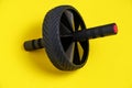 Sports simulator roller for press on yellow background.