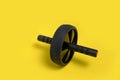 Sports simulator roller for press on yellow background.