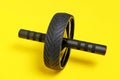 Sports simulator roller for press on yellow background.