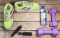 Sports sneakers, dumbbells, drinking water on a wooden background, flat lay