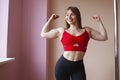 Sports strong girl bodybuilder shows biceps and smiles, woman with big muscles