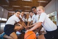Sports teacher and school kids forming hand stack in basketball court