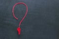 Sports whistle on a red lace. It is laid out in the form of a question mark. Concept- sport competition, referee, statistics, chal