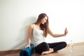 Woman sitting on floor and making selfie on smartphone in fitness gym Royalty Free Stock Photo