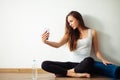 Woman sitting on floor and making selfie on smartphone in fitness gym Royalty Free Stock Photo