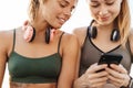 Sports women friends sitting outdoors using mobile phone