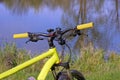 A sports yellow black bike stands in the green grass on the shore