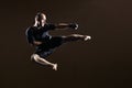 Sportsman in black gloves and a black T-shirt beat a kick in the jump