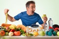 Sportsman eating apple funny showing fruits and vegetables and scale