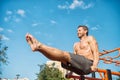 Sportsman exercising on parallel bars outdoors on blue sky