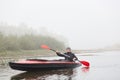 Sportsman in kayak, padding in foggy river, spending his free time outdoors, doing water sport, posing with oar in hands, rowing