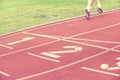 Sportsman legs in running shoes on stadium red track.
