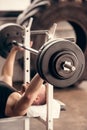 sportsman lifting barbell in gym with weight plates