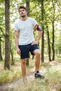 Sportsman with mobile phone in handband standing in forest