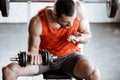 Sportsman with opened mouth exercising with dumbbell and looking at probiotic pills