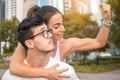 Sportsman piggybacking sportswoman while she showing muscles outdoors. Royalty Free Stock Photo