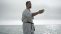 Sportsman practicing hand position training karate near sea. Man learn technique