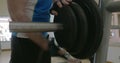 Sportsman putting disk weight on the barbell in