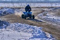 Sportsman racer man fulfills a fast ride on the ATV on the road extreme. The race track is very uneven. A sunny winter day