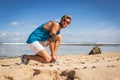 sportsman with smartphone armband in sunglasses tying shoelaces on sneakers