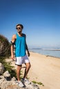 sportsman in sunglasses standing on rocks on seashore