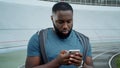 Sportsman texting on smartphone at track. Guy reading good news on mobile phone Royalty Free Stock Photo