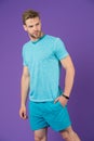 Sportsman in tshirt and shorts on violet background. Man in blue casual clothes. Macho in active wear for workout or training on p