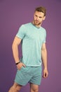 Sportsman in tshirt and shorts on violet background. Man in blue casual clothes. Macho in active wear for workout or