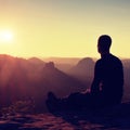 Sportsmann hiker in black sportswear sit on mountain top and take a rest. Tourist watch down to morning misty valley.