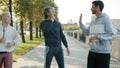 Sportspeople friends meeting outdoors doing high-five then jogging together in city street