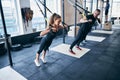 Sportspeople performing a strength training exercise on a suspension trainer