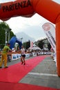 Sportswoman arriving at the finish of `Lecco city - Resegone mountain` running marathon event.