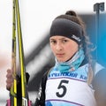 Sportswoman biathlete Knyazeva Elizaveta with skis in hands and rifle behind her after skiing and rifle shooting. Junior