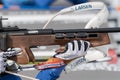 Sportswoman biathlete rifle shooting in prone position. Selective focus extreme closeup shot. Biathlete in shooting