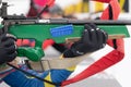 Sportswoman biathlete rifle shooting in prone position. Selective focus extreme closeup shot. Biathlete in shooting