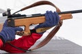 Sportswoman biathlete rifle shooting in prone position in shooting range. Selective focus, extreme close-up shot