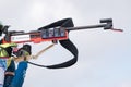 Sportswoman biathlete rifle shooting in standing position. Selective focus, extreme close-up. Biathlete in shooting area