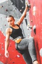 Sportswoman climber moving up on steep rock, climbing on artificial wall indoors. Extreme sports and bouldering concept Royalty Free Stock Photo
