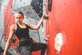 Sportswoman climber moving up on steep rock, climbing on artificial wall indoors. Extreme sports and bouldering concept