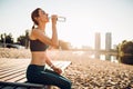 Sportswoman drinking water on riverbank