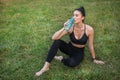 Sportswoman drinking water sitting on the grass Royalty Free Stock Photo